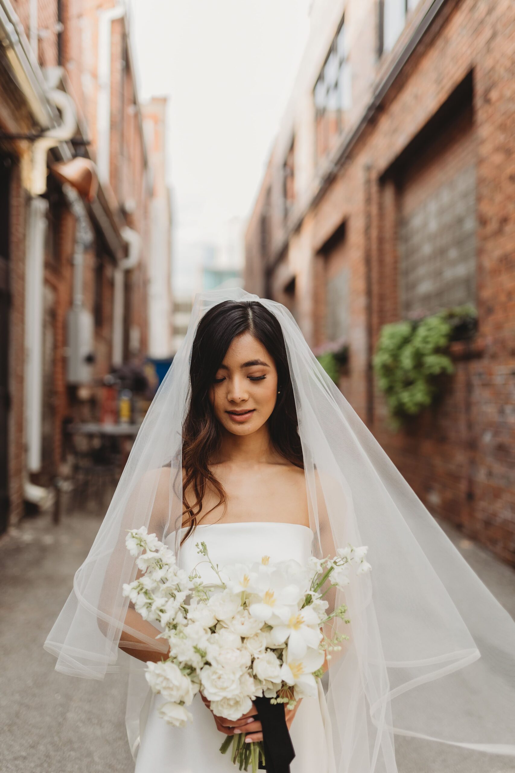 bride in veil with an all white bouquet at Outreach Event Space wedding