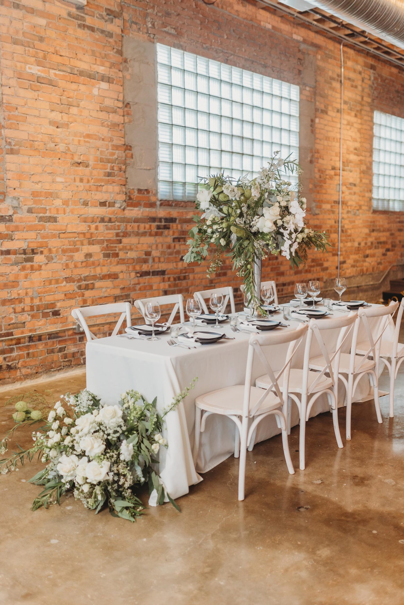 elegant head table with lush centerpiece and floor piece at Outreach Event Space wedding