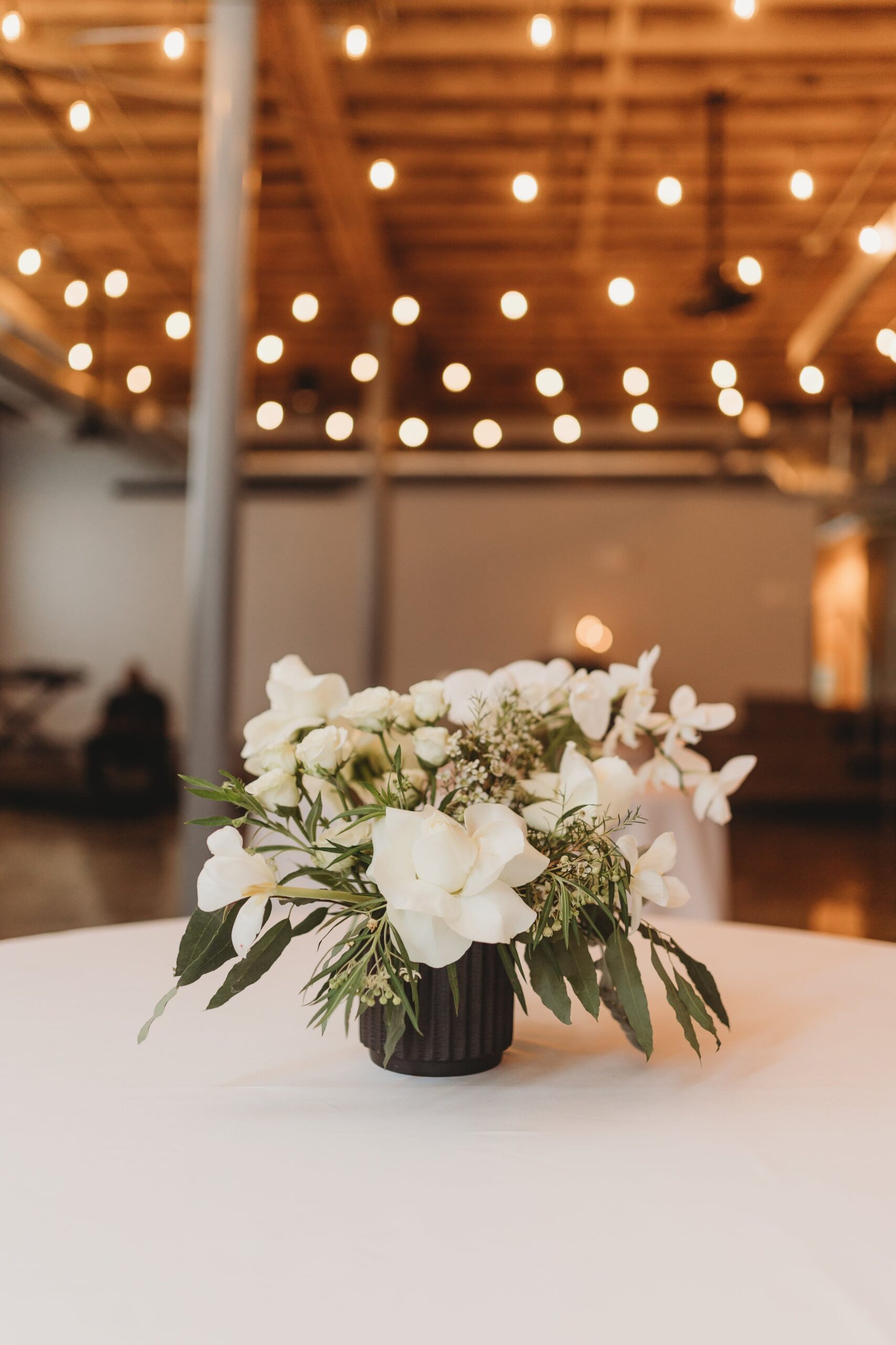 small white centerpiece in a black vase at an Outreach Event Space wedding
