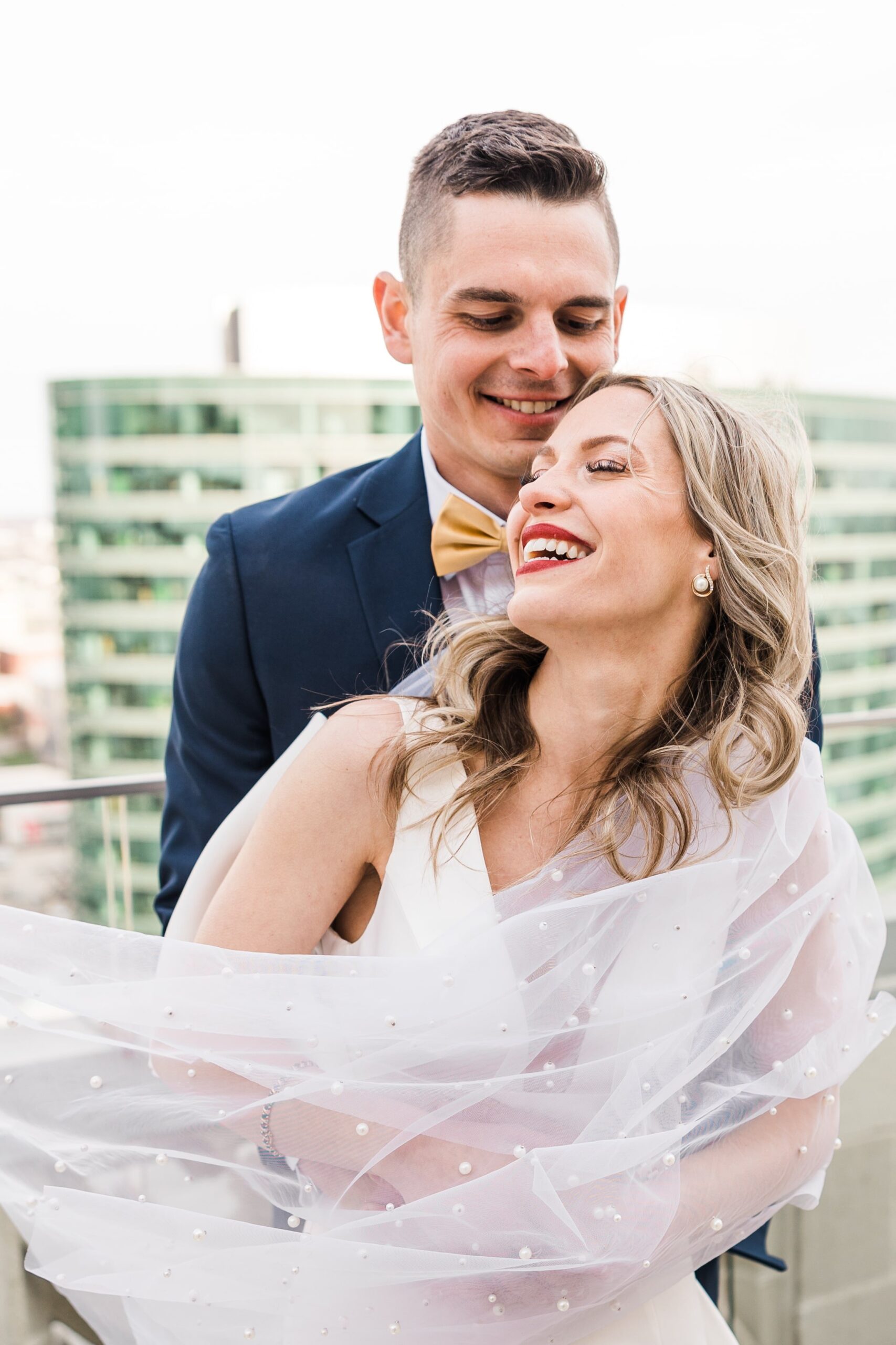 Couple hugging and smiling on the Starlight Terrace at Hotel Kansas City. The bride's veil is studded with pearls
