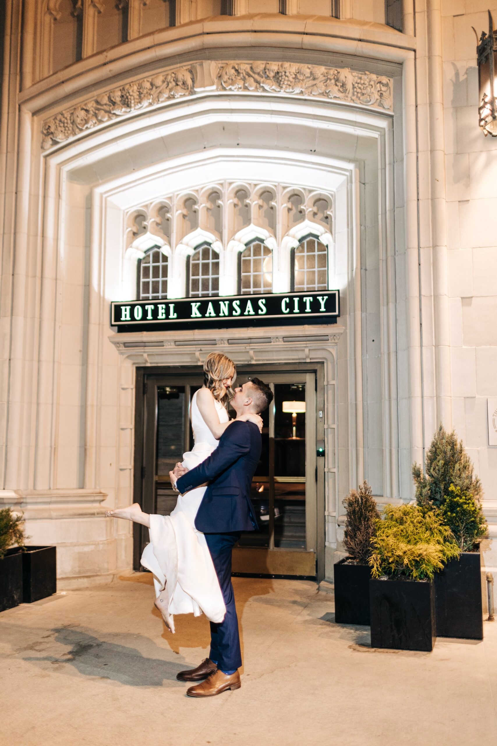 Groom lifting bride in front of Hotel Kansas City 