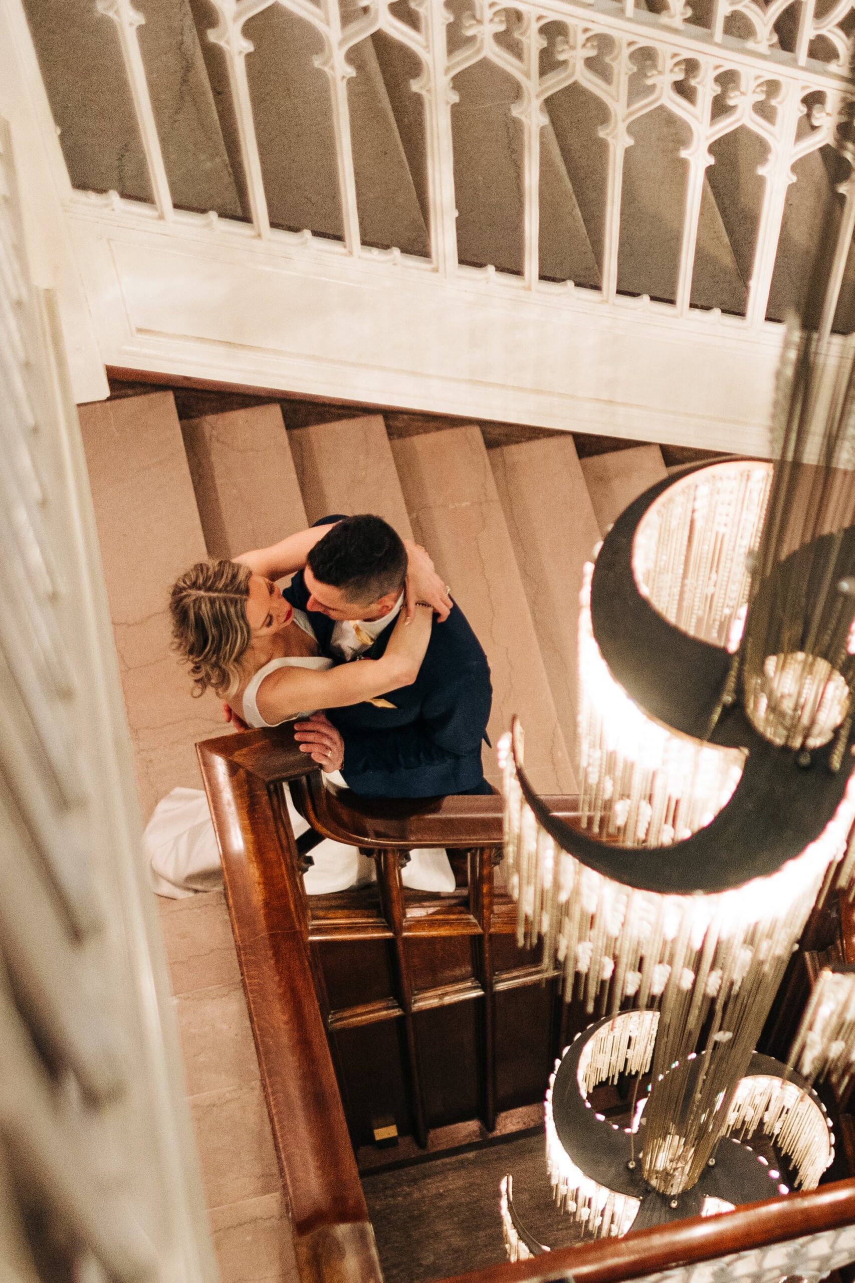 Bride and groom hug under the chandelier at Hotel Kansas City