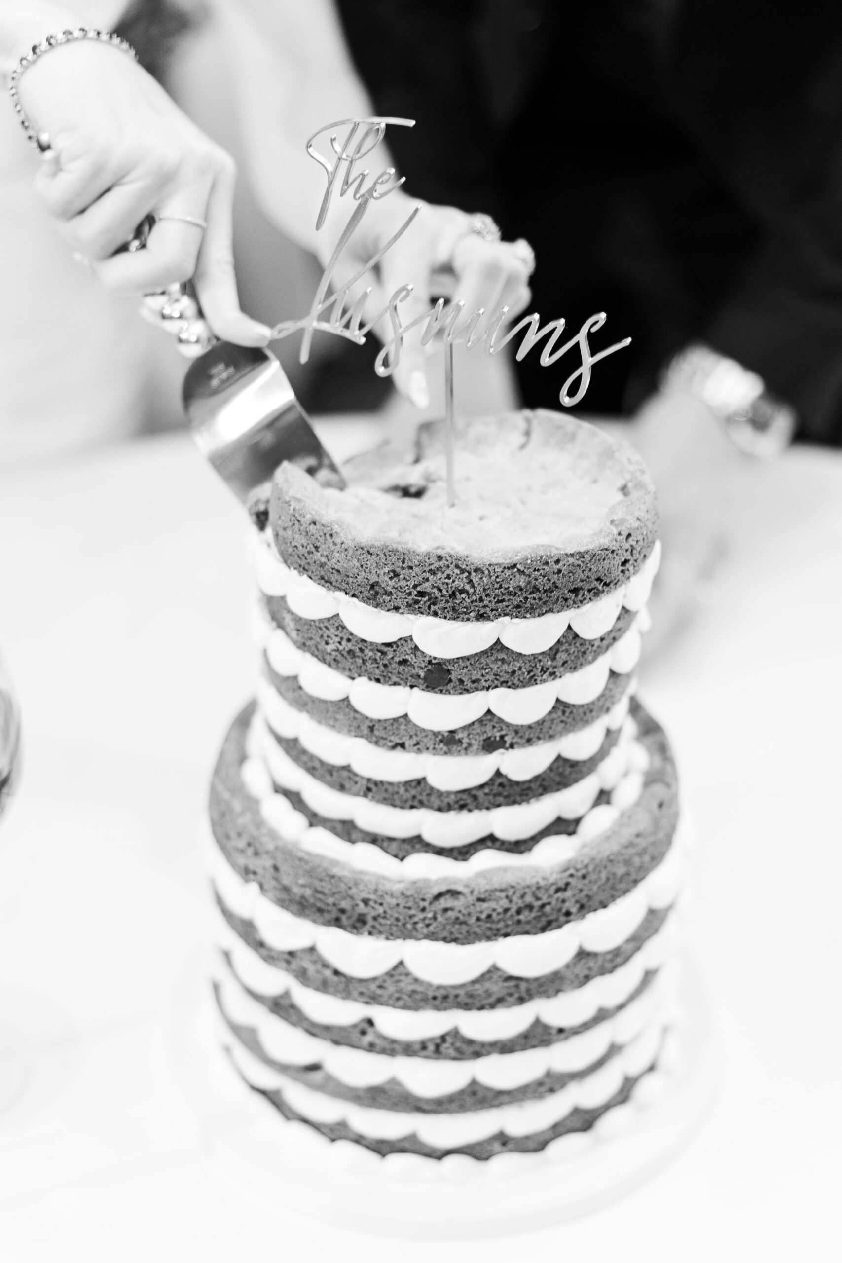 Black and white image of a bride cutting their wedding cookie cake