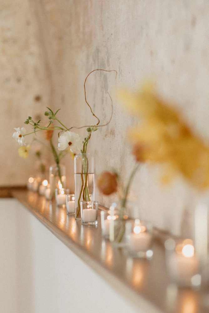 long row of votive candles and bud vases with flowers
