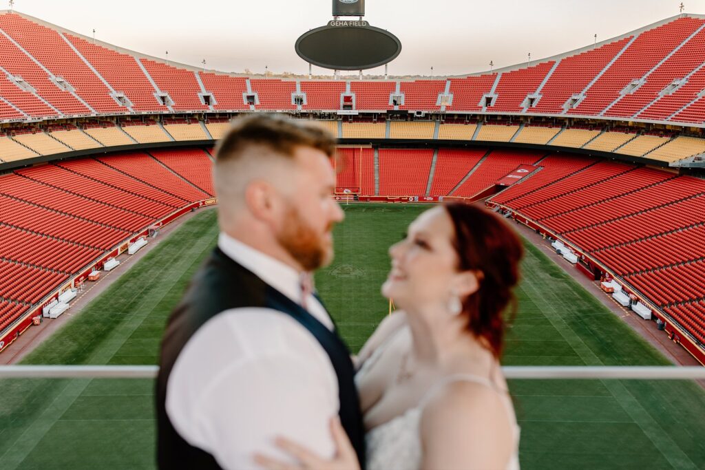 couple on their wedding day at arrowhead with the stadium in the background