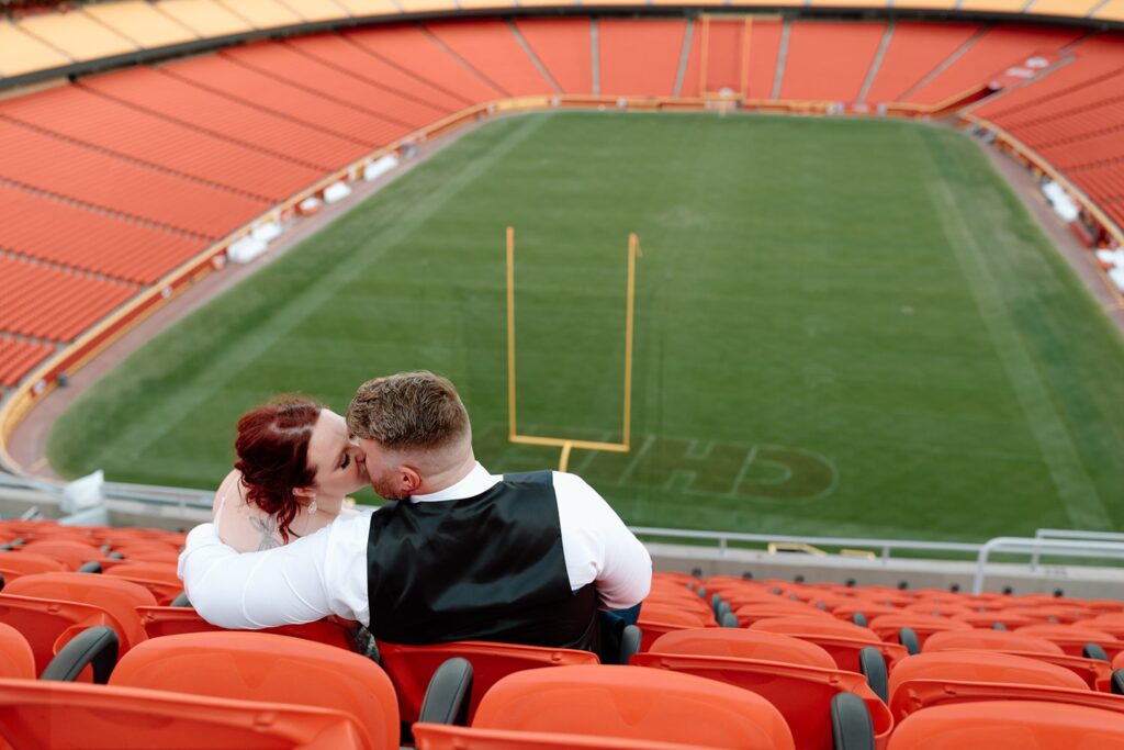 bride and groom kissing in the stands at arrowhead