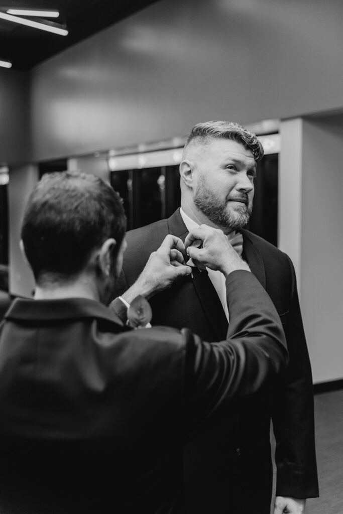 groom getting boutonniere pinned in the locker room at arrowhead 