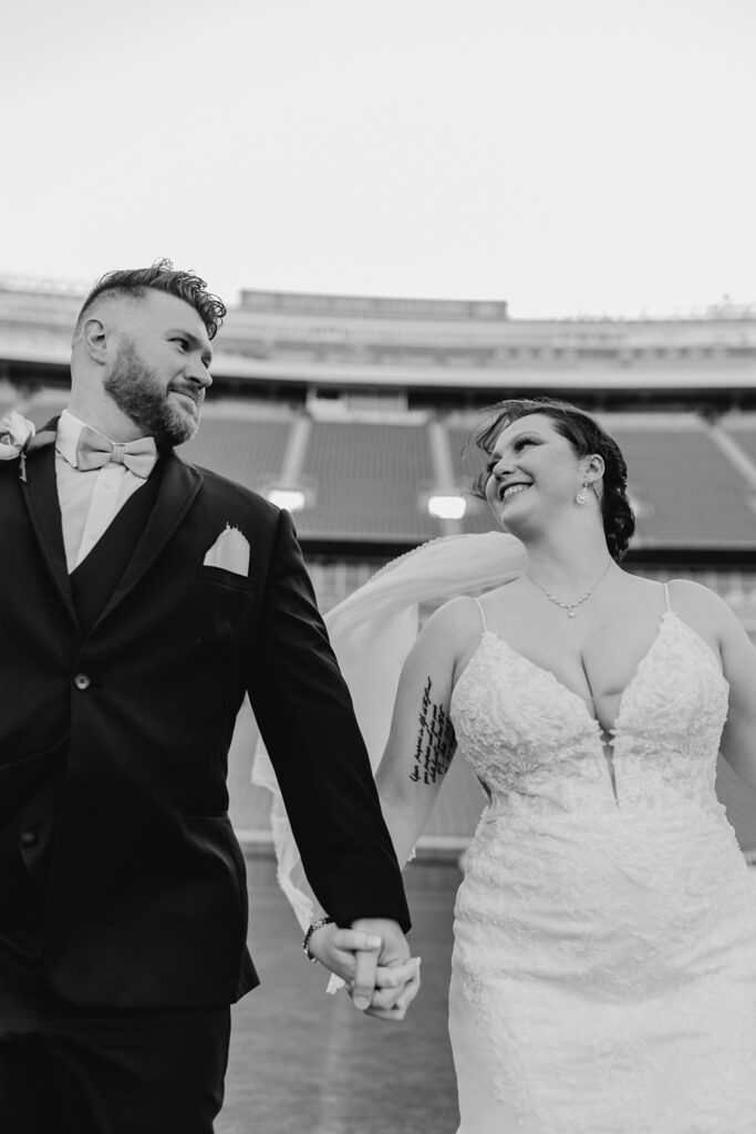 bride and groom on the field at their arrowhead stadium wedding; black & white