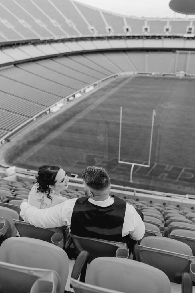 couple talking in the stands at arrowhead on their wedding day; black & white