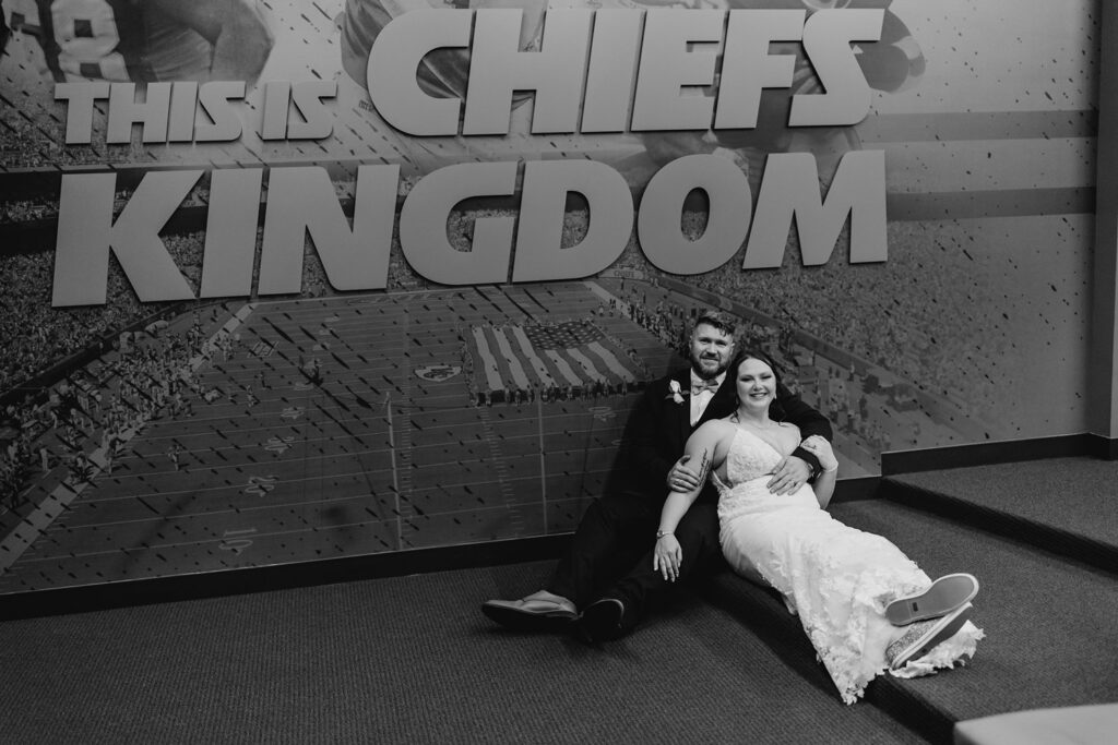 bride & groom in front of chiefs kingdom sign