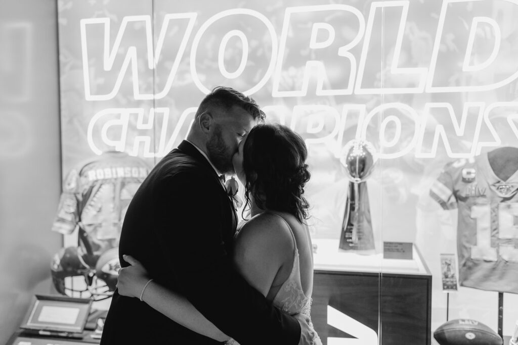 bride and groom in front of the vince lombardi trophies at arrowhead; black & white