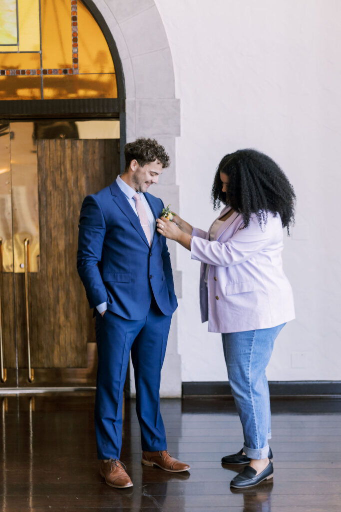 wedding planner adjusting a groom's boutonniere