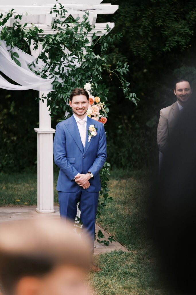 groom watching the bride walk down the aisle at countryside chalet wedding ceremony